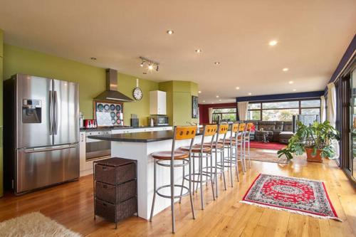 a kitchen with a bar with stools and a refrigerator at Harbour Lodge in  Lyttelton
