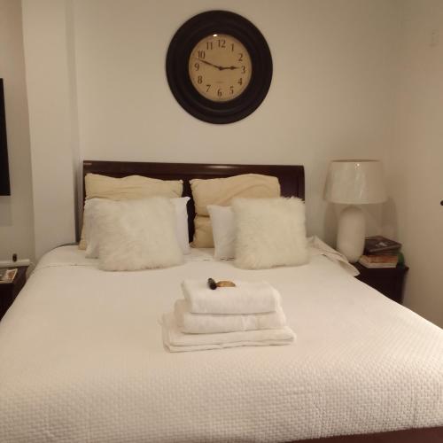 a bed with towels and a clock on the wall at Elegant BnB in Bulawayo