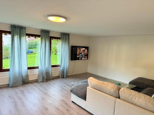 een woonkamer met een bank en een groot raam bij Beutiful house with large garden . in Lilla Edet