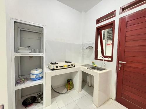 a white kitchen with a sink and a red door at Graha permata kota in Tjakranegara
