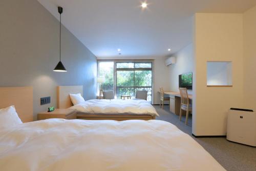 a hotel room with two beds and a table and a desk at HEKISUIEN in Minatomiya
