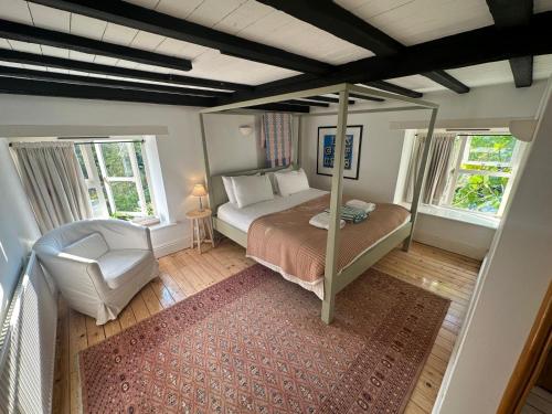 a bedroom with a bed and a chair and two windows at Cotswold Cottage in Steeple Aston