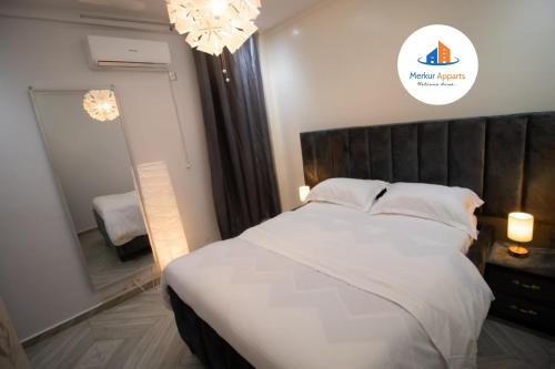 Un dormitorio con una cama blanca y un espejo. en Merkur Apparts, Studio Meublé Haut-Standing, en Djoungolo