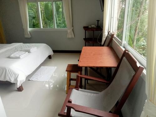 a room with a table and a bed and a table and chair at Kanda Hill Resort in Ban Na Sok