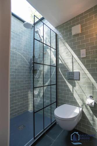 a bathroom with a toilet and a glass shower at The Hideout-Boutique Cabin, Estuary View & Parking in Salcombe