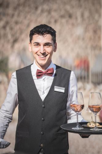 a man holding a tray with two glasses of wine at Schloss Hotel Korb in Appiano sulla Strada del Vino