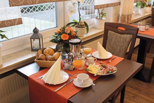 een tafel met ontbijtproducten en sinaasappelsap erop bij Pension Haus Waldfrieden, MeineCardPlus inklusive in Willingen