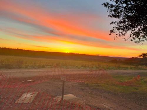 a sunset over a dirt road with a fence at Middlehead Huts in Newton