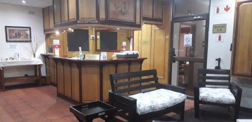 a bar in a room with two chairs and a counter at Kalahari Lodge Kimberley in Kimberley