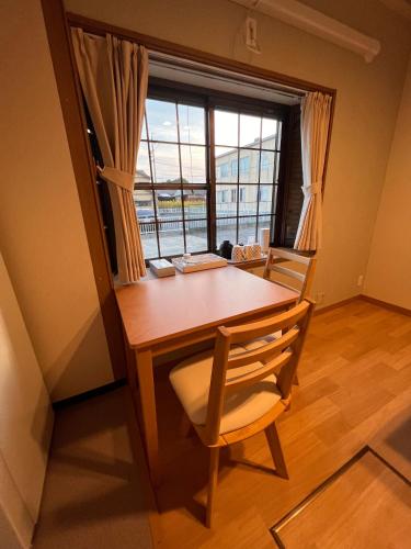 a wooden table with a chair and a window at Check in is available from 12 PM Yokkaichi Miyamadocho House B in Yokkaichi