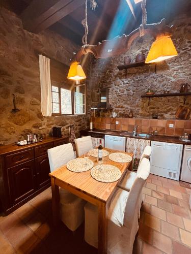 a kitchen with a wooden table and white chairs at Casa Rural Los Cuartos de Gredos in Los Cuartos