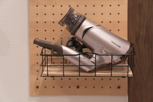 a hair dryer on a wire rack on a wall at 広島ゲストハウス Nice Day in Hiroshima
