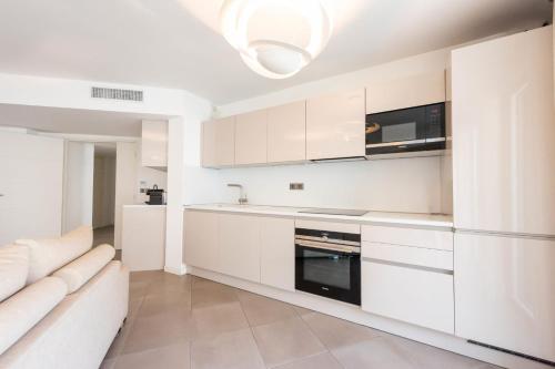 - une cuisine blanche avec des placards blancs et un canapé dans l'établissement 3-Br Apartment with Pool Parking & Beaches 100m away, à Cannes