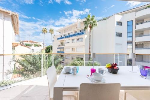 une table et des chaises blanches sur un balcon avec vue sur un bâtiment dans l'établissement 3-Br Apartment with Pool Parking & Beaches 100m away, à Cannes