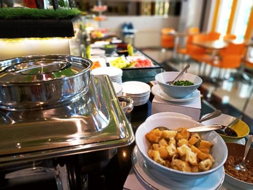 a buffet line with dishes of food on a table at Halogen Hotel Airport Surabaya in Sidoarjo