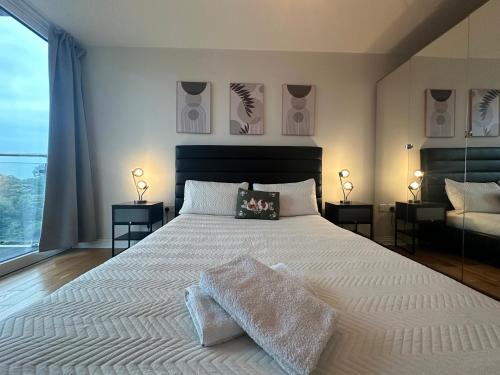a bedroom with a large white bed with two lamps at Lovely flat in Kingston Town in Kingston upon Thames