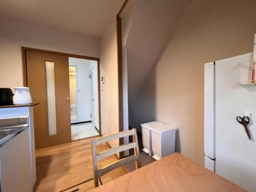 a small room with a kitchen with a door and a chair at Check in is available from 12 PM Yokkaichi Miyamadocho House B in Yokkaichi