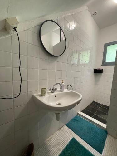 une salle de bain blanche avec un lavabo et un miroir dans l'établissement Domaine La Gazaille de Camille, à Le Temple-sur-Lot