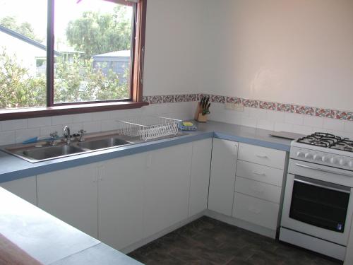 a kitchen with a sink and a stove and a window at Rainbow House in Denmark