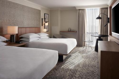 a hotel room with two beds and a table at Sheraton Parkway Toronto North Hotel & Suites in Richmond Hill