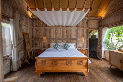 a bedroom with a bed in a room with wooden walls at Meraki Luxury Villa in Pemuteran