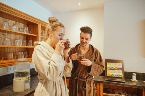 a man and woman standing in a kitchen taking a picture at Hotel Vitalquelle Montafon in Schruns-Tschagguns