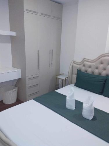 a bedroom with a white bed with green pillows and a green blanket at Matina Enclaves 2BR with Wifi Near SM Mall in Davao City