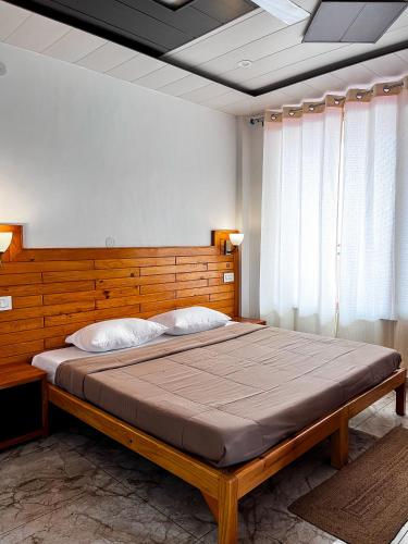 a bedroom with a large bed with a wooden headboard at Yutori Stays in Dharamshala