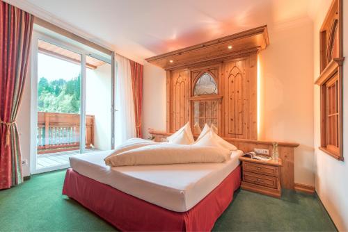a bedroom with a large bed and a window at Hotel Vitalquelle Montafon in Schruns-Tschagguns