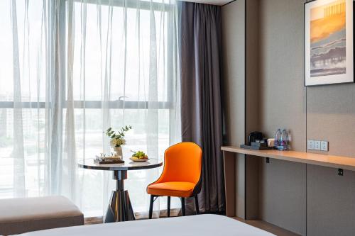 a hotel room with an orange chair and a table at Poltton Century Hotel Yangjiang Jinshan Road in Dongcheng