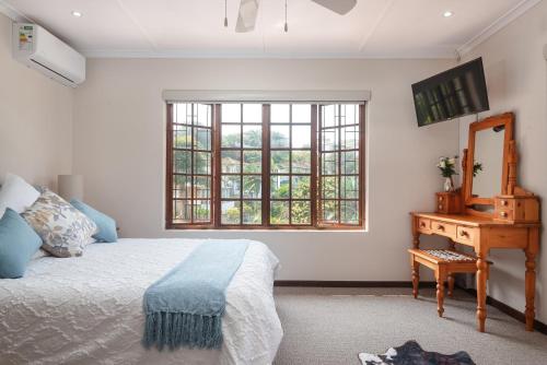 a bedroom with a bed and a dresser and a window at Kingfisher Cove in Ballito