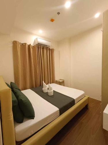 a bedroom with a large bed with green pillows at Matina Enclaves 2BR with Wifi Near SM Mall in Davao City