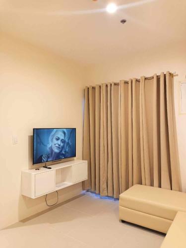 a living room with a flat screen tv and curtains at Matina Enclaves 2BR with Wifi Near SM Mall in Davao City