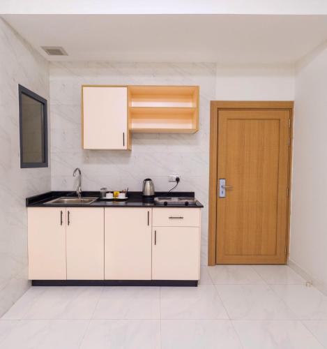 a kitchen with white cabinets and a wooden door at Liza Hotel in Muscat