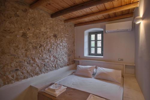 a bedroom with a bed in a room with a window at Elegantly restored traditional cottage in Logothetiánika