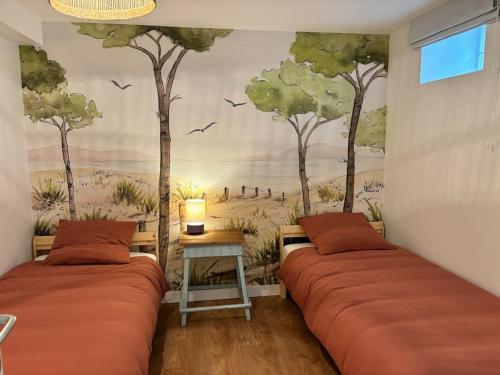- 2 lits dans une chambre avec des arbres sur le mur dans l'établissement Appartement rue des artistes, à Camaret-sur-Mer