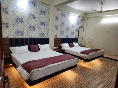 two beds in a room with blue and white wallpaper at Baldeshwar homestay in Ujjain