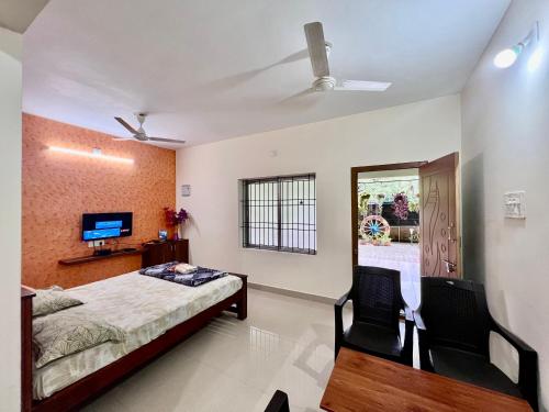 a bedroom with a bed and two chairs and a tv at Karkera Family Homestay in Malpe