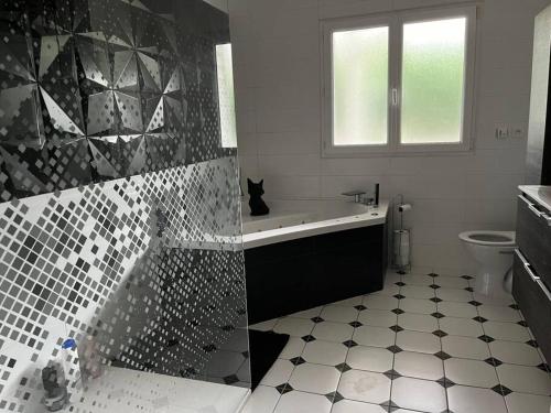 - une salle de bains avec un chat noir assis sur une baignoire dans l'établissement Villa 180m2 proche Lac Hourtin, à Hourtin