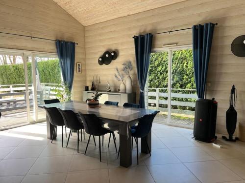 une salle à manger avec une table et des chaises noires dans l'établissement Villa 180m2 proche Lac Hourtin, à Hourtin