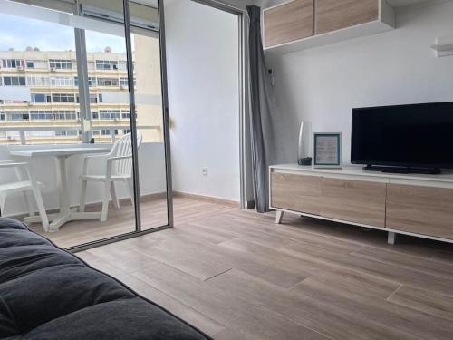 ein Wohnzimmer mit Flachbildfernseher und großem Fenster in der Unterkunft Design seaview flat next to Yumbo in Playa del Ingles