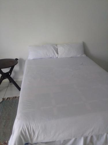 een bed met witte lakens en een stoel in een kamer bij 17 on Driffield in East London