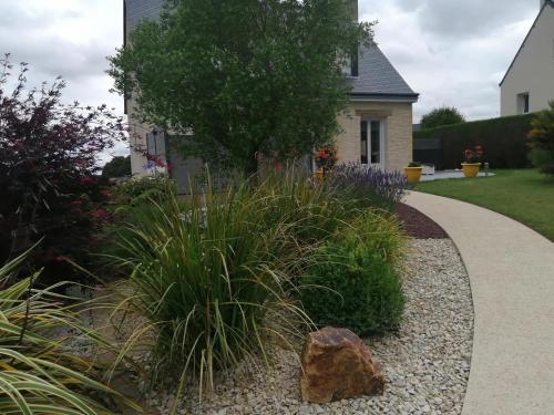 un giardino con piante e un vialetto di Maison charmante à Trédaniel avec jardin et terrasse a Trédaniel