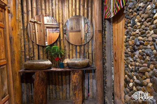 two mirrors on a wooden wall with two sinks at Thai House Pu Luong - Century Old Stilt House with Terrace Views in Hương Bá Thước