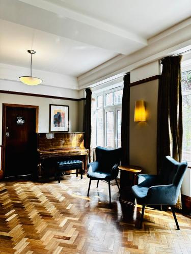 a living room with a piano and chairs at Vincent House London Residence in London
