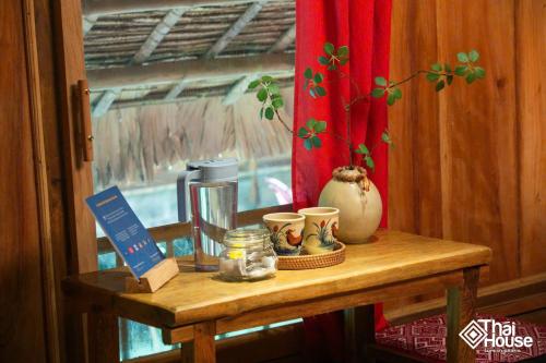 un tavolo di legno con tazze e altri articoli di Thai House Pu Luong - Century Old Stilt House with Terrace Views a Hương Bá Thước