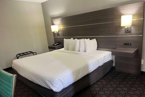 a hotel room with a large bed with white sheets at Days Inn by Wyndham Wagoner in Wagoner