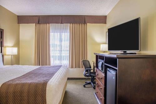 a hotel room with a bed and a flat screen tv at Days Inn by Wyndham Cranbrook Conference Centre in Cranbrook