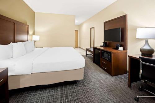 a hotel room with a bed and a flat screen tv at Comfort Inn & Suites High Point - Archdale in Archdale