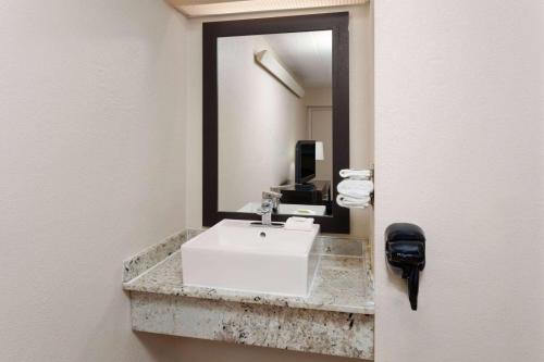 a bathroom with a white sink and a mirror at Travelodge by Wyndham Peoria in Peoria